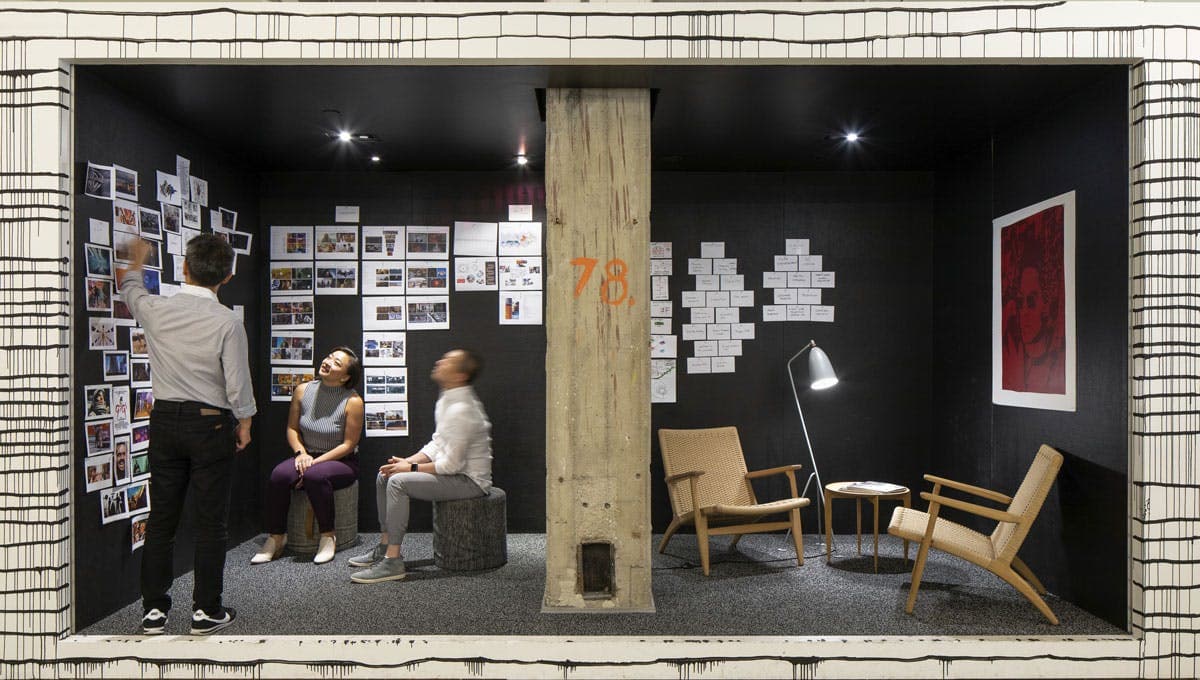 Team brainstorming with photo wall and concrete column inside a creative workshop space